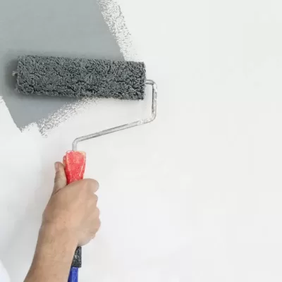 Paint,Roller.,Painting,With,Gray,Paint,Over,A,White,Wall